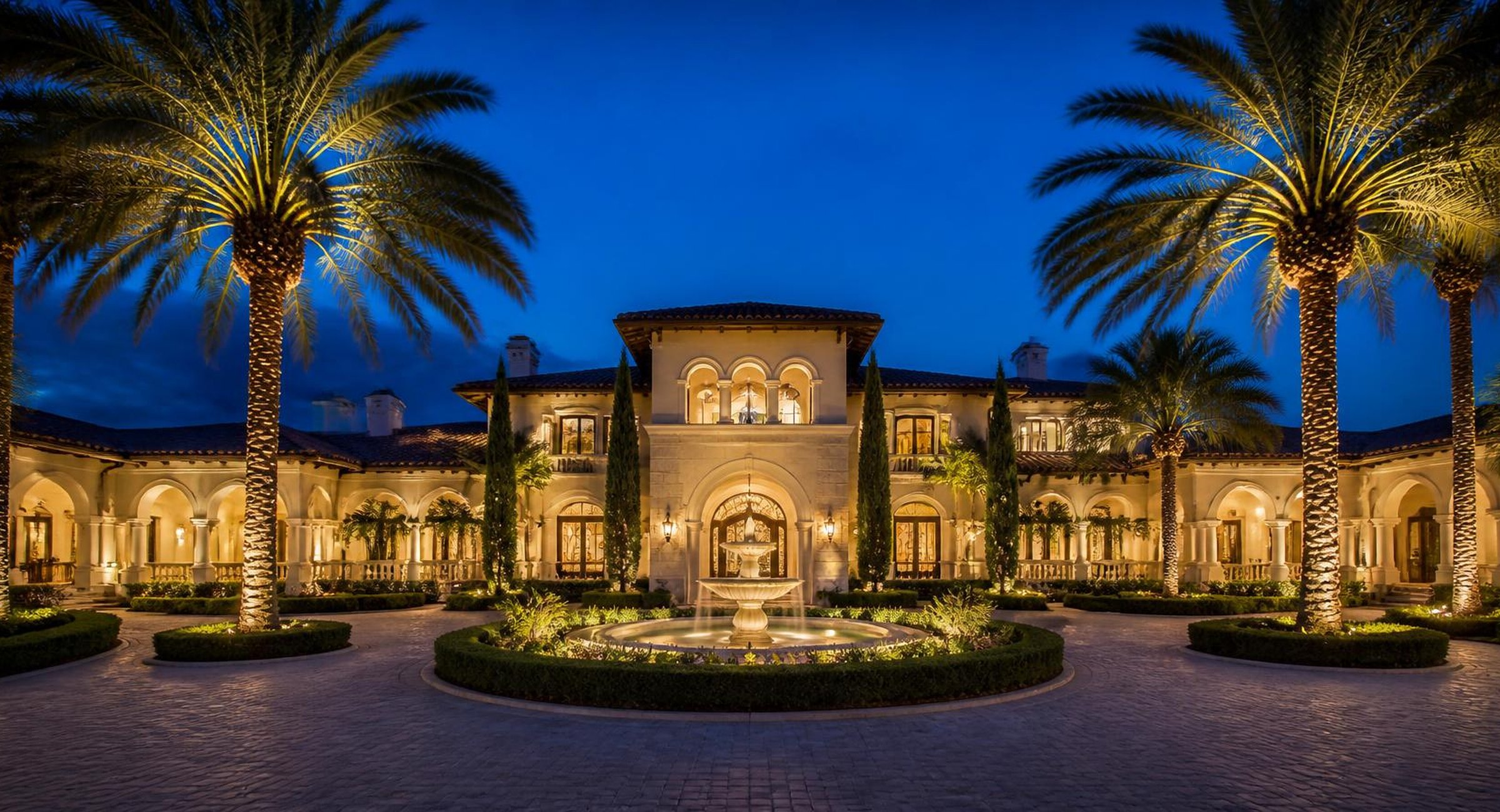 Mediterranean estate with fountain motor court at dusk